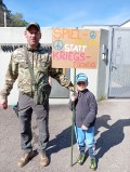 Vater mit Sohn und Schild vor den Toren des NATO-Hauptquartiers